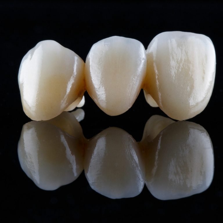three beautiful dental crowns of natural color on black glass with reflection